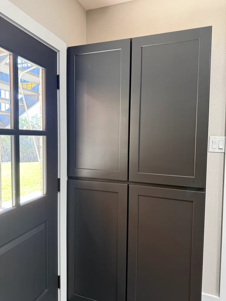 View of a black cabinet next to a door in a well-lit interior space.
