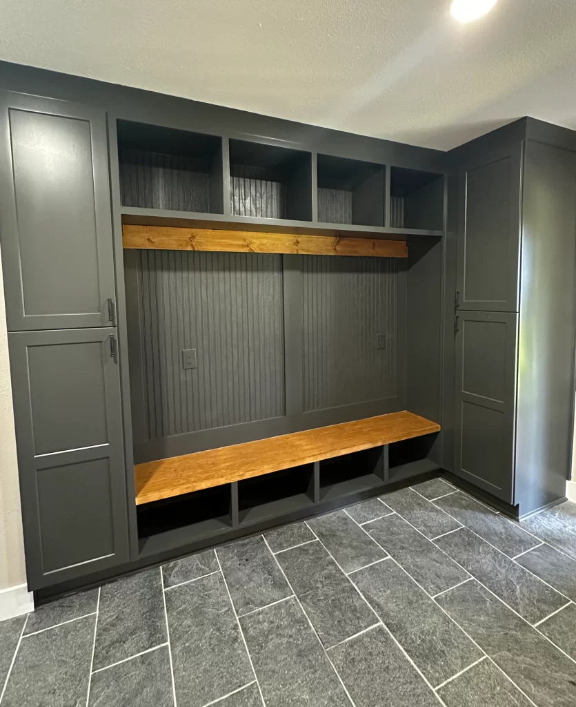Modern entryway mudroom featuring gray cabinetry with open shelving and a wooden bench.
