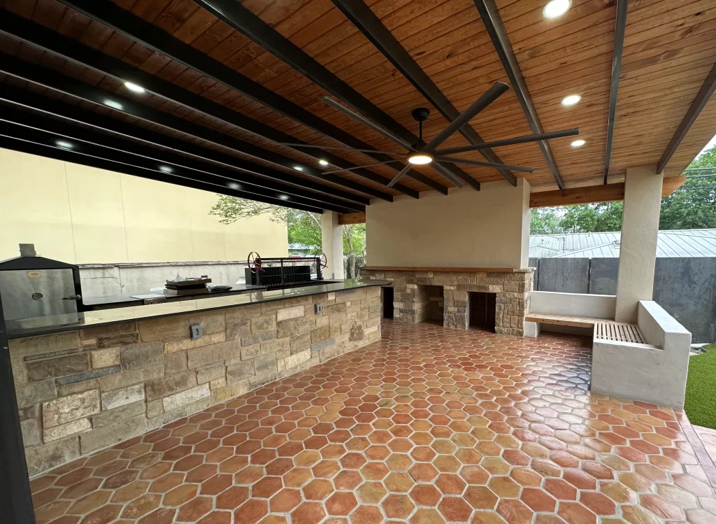 Outdoor kitchen area featuring a stone countertop, wooden ceiling, and tiled flooring.